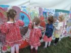 Cztery małe dziewczynki w kolorowych ubraniach podczas malowania muralu